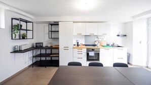 A modern kitchen with white cabinets, a wooden countertop, and a dining table.