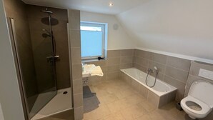 Een moderne badkamer met een inloopdouche, een badkuip en een toilet.