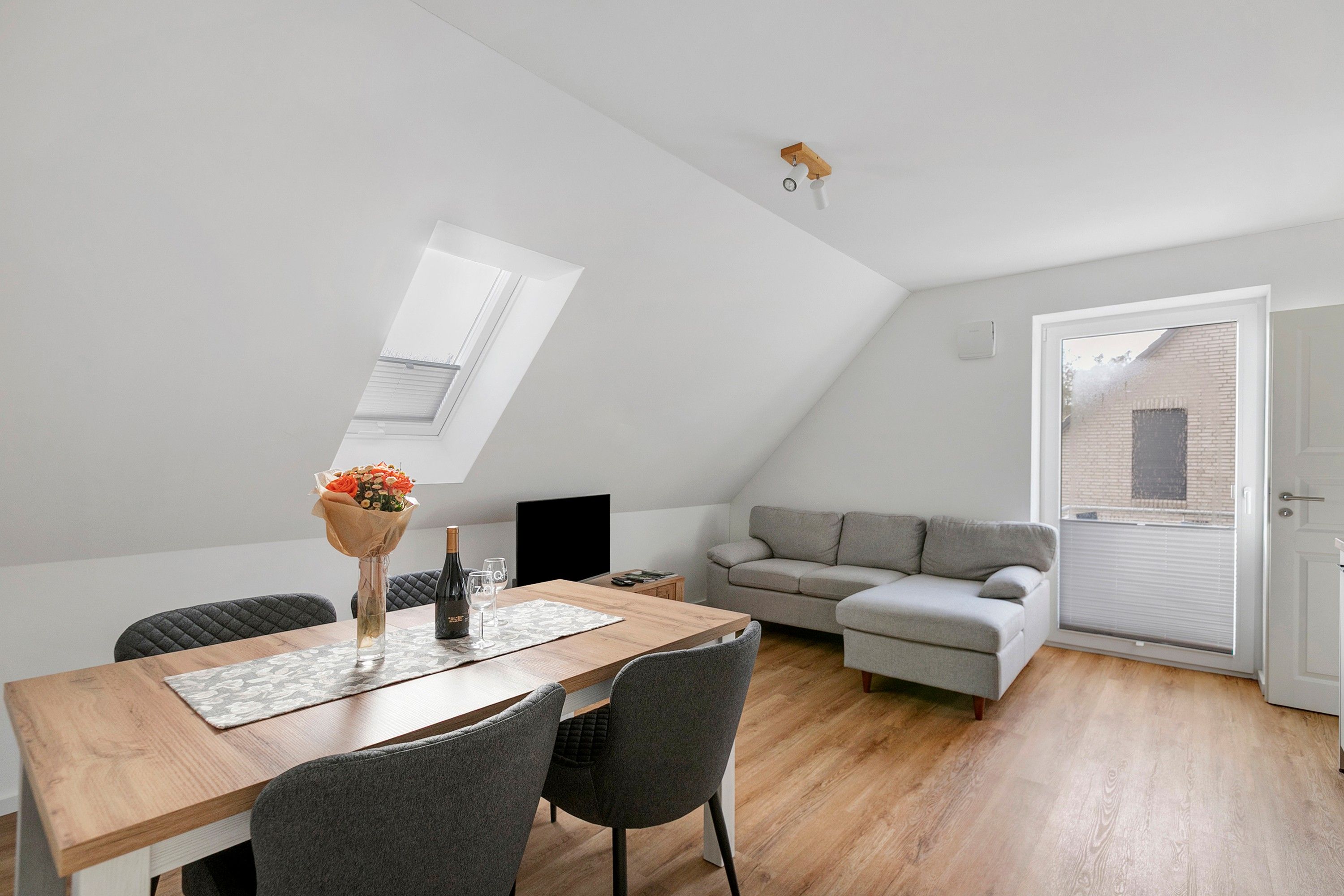 Ein modernes Loft-Apartment mit Essbereich, einer Couch und einem großen Fenster.