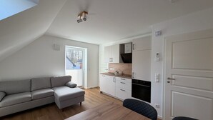 Een modern loft appartement met een eethoek, kitchenette en een groot raam.