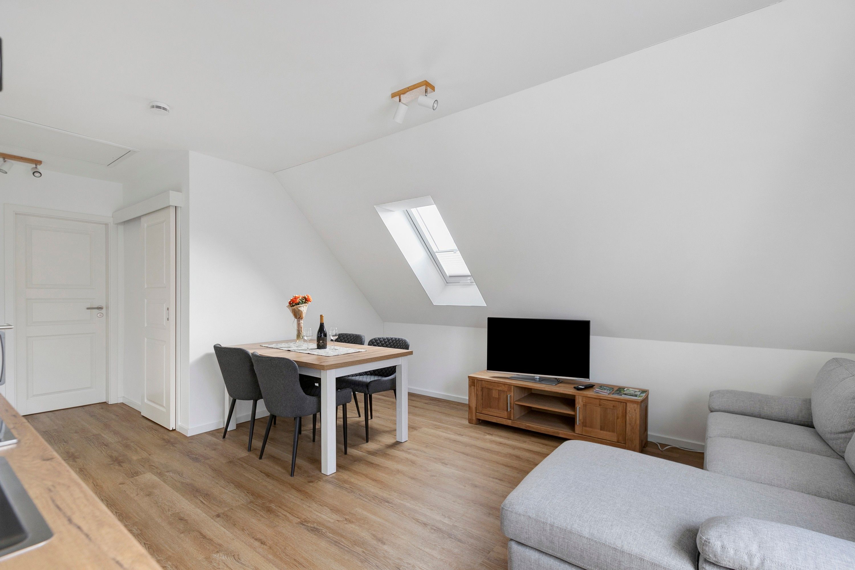 A modern loft apartment with a dining area, a living room, and a TV.
