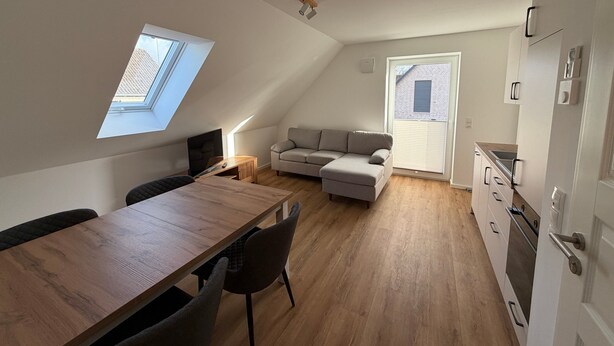 Een modern appartement met een eethoek, een bank, een keuken en een dakraam.