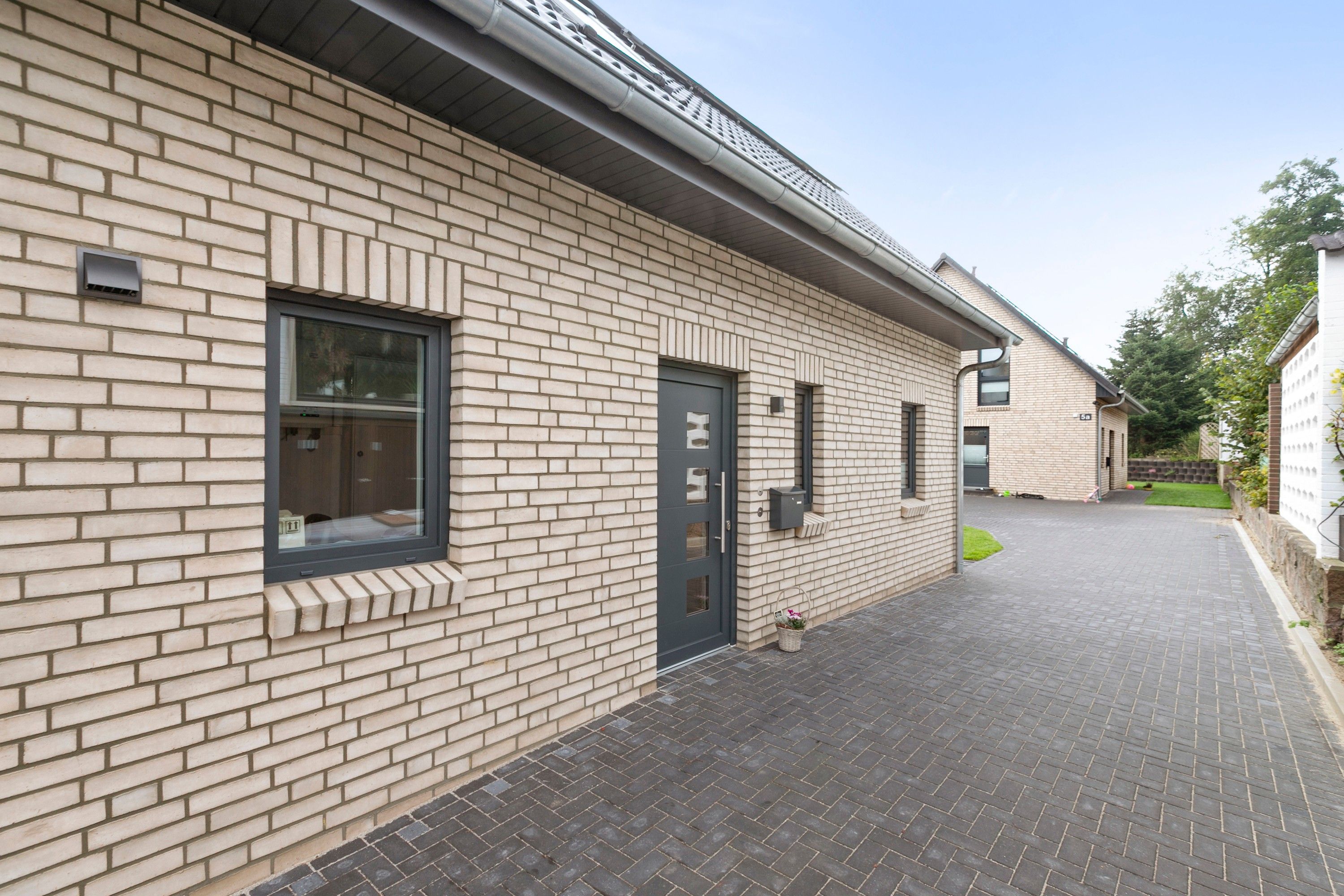 Un bâtiment à la façade en briques, avec une porte noire et une fenêtre donnant sur l’intérieur.