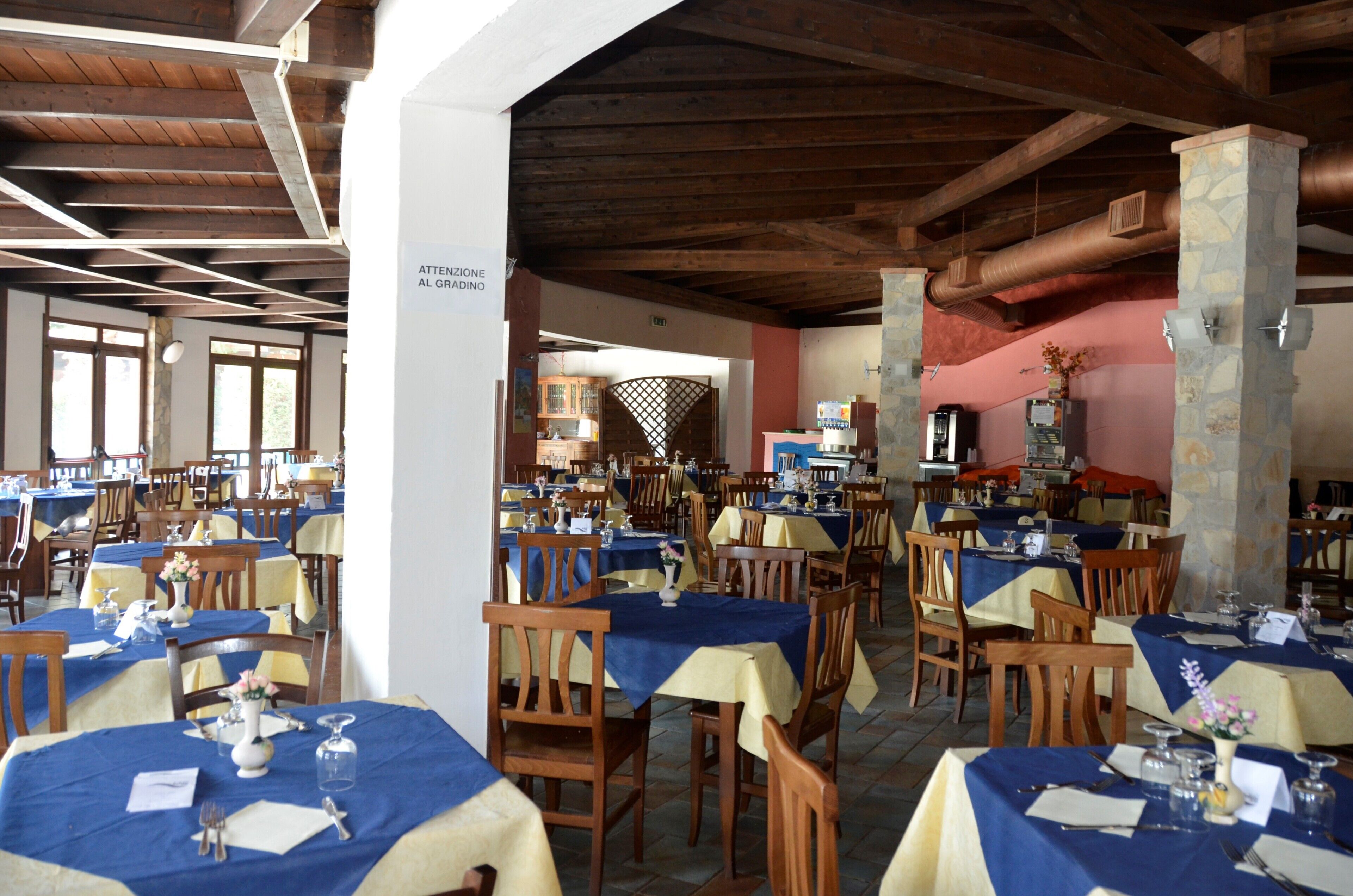 Un restaurant avec plusieurs tables, des chaises en bois et un pilier en pierre.