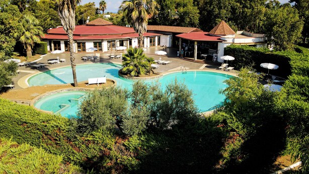 A resort with a large pool, lounge chairs, and a covered patio area. - FRUIT VILLAGE HOLIDAY BEACH (Diamante)