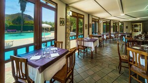 A restaurant with tables and chairs, large windows, and a view of a pool. - FRUIT VILLAGE HOLIDAY BEACH (Diamante)