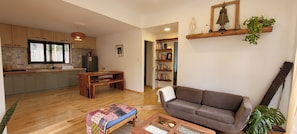 Una sala de estar con un sofá, una mesa de centro, un banco de madera y una estantería.