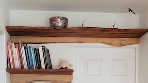 A room with a white door, wooden shelves with books, a small decorative item, and a bowl on the top shelf.