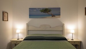 Ein Schlafzimmer mit einem Bett, zwei Nachttischen, einer Ablage und einem Wandbild von einem Baum.