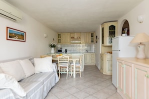 Un espacio habitable compacto con kitchenette, comedor y sofá.