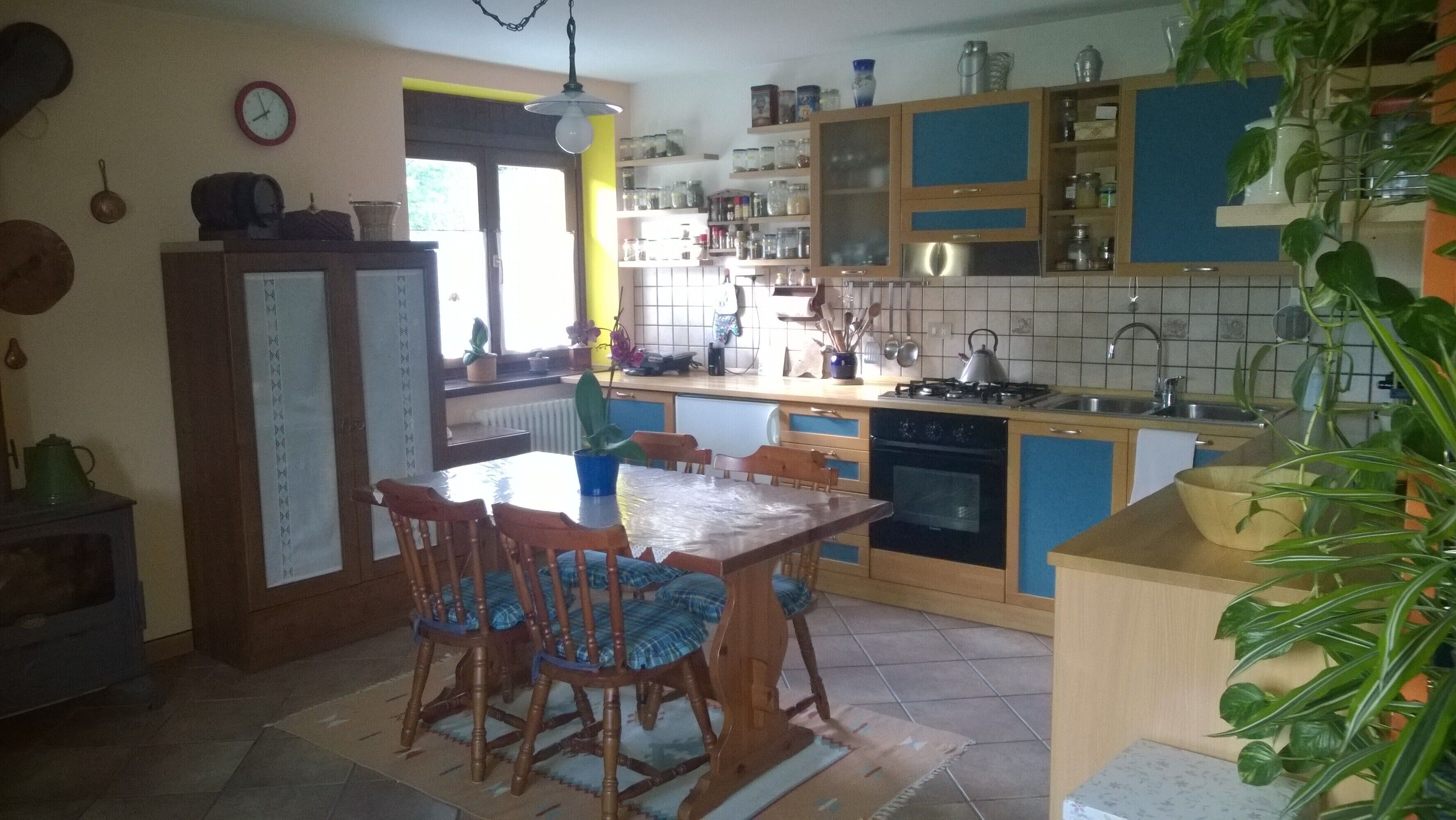 Une cuisine avec des meubles de rangement en bois, une table à manger avec des chaises, une cuisinière et un évier.
