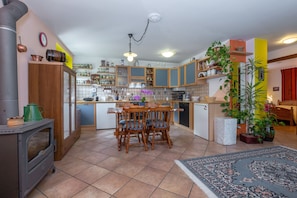 Una cocina con armarios de madera, estufa, una mesa de comedor con sillas y una alfombra.