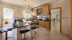 Uma cozinha moderna com ilha central, banquetas de bar e área de jantar com mesa e cadeiras.