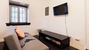 Ett modernt vardagsrum med en soffa, en tv som är monterad på väggen och en inbyggd mediabänk.