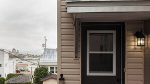Ett bostadshus med en ytterdörr, en liten veranda och ett synligt garage.
