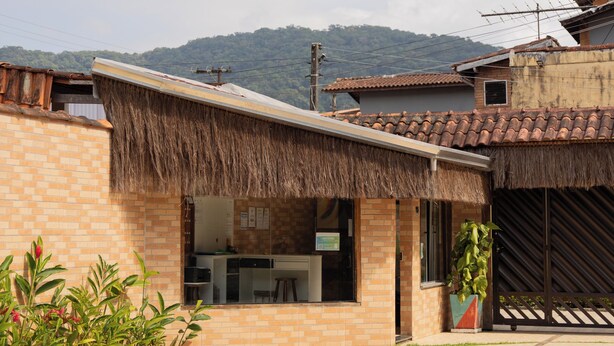 Ein Haus mit Ziegeldach, Ziegelaußenwand und einem Anbau mit Strohdach.