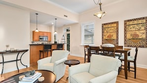 A modern living room with a dining area, wooden cabinets, and artwork on the walls. - Historic Biltmore Village Retreat | 2 King En-Suites | Fireplace | Pets Welcome (Asheville)