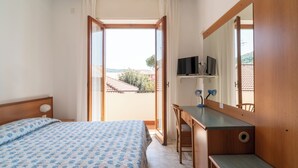 Una camera da letto con un letto, una scrivania, uno specchio e vista all'esterno.
