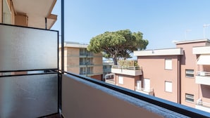 Un balcone con vista su edifici vicini e un albero.
