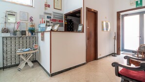 Un'area receptione con scrivania, sedie e diversi poster informativi alle pareti.