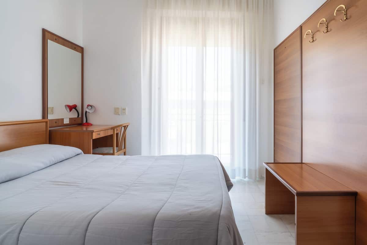 Un dormitorio con cama, un escritorio de madera, un espejo y un armario.