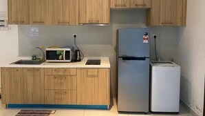Eine kleine Küche mit Holzausstattung, einer Mikrowelle, einem Kühlschrank und einem Spülbecken.