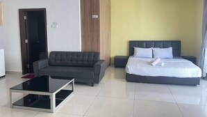 Ein modernes Hotelzimmer mit einer Couch, einem Bett, einem Glastisch und einem Holzschrank.