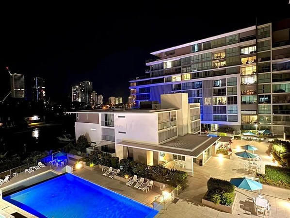 A modern hotel with a rooftop pool, outdoor seating, and a view of the city skyline.