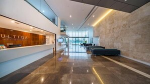 A modern hotel lobby with a reception desk, seating area, and a view of the city. - Riverfront Heated Pool, Gym, Sauna Steps to Casino (Broadbeach)