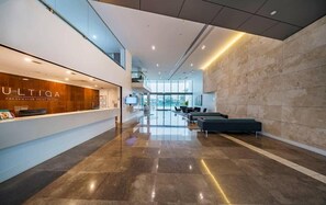 A modern hotel lobby with a reception desk, seating area, and a view of the city.