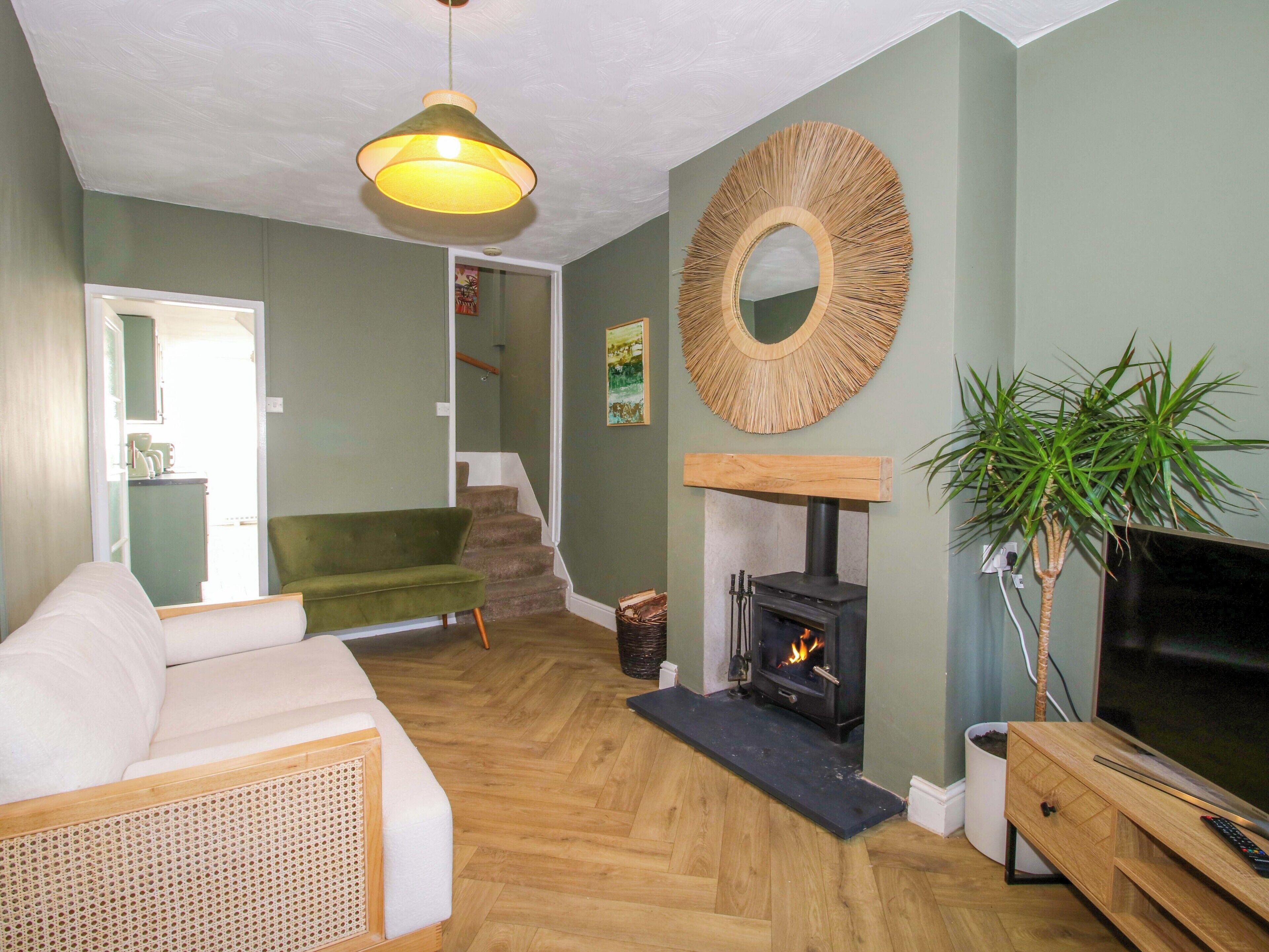 A living room with a sofa, a fireplace, a television, and a staircase leading to another room.