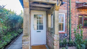 A wooden porch with a white door, a small window, and a brick wall. - Cheshire Views (Malpas)