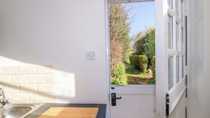 A kitchen with a wooden cutting board, a sink, and a window with a view of greenery. - Cheshire Views (Malpas)
