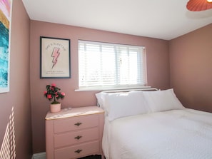 Un dormitorio con cama, cómoda, ventana con persianas y una cita enmarcada en la pared.