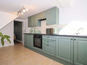 A kitchen with teal cabinets, a black oven, a microwave, and a coffee maker. - Cheshire Views (Malpas)