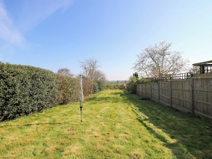 A grassy yard with a wooden fence, a metal pole, and a hedge. - Cheshire Views (Malpas)
