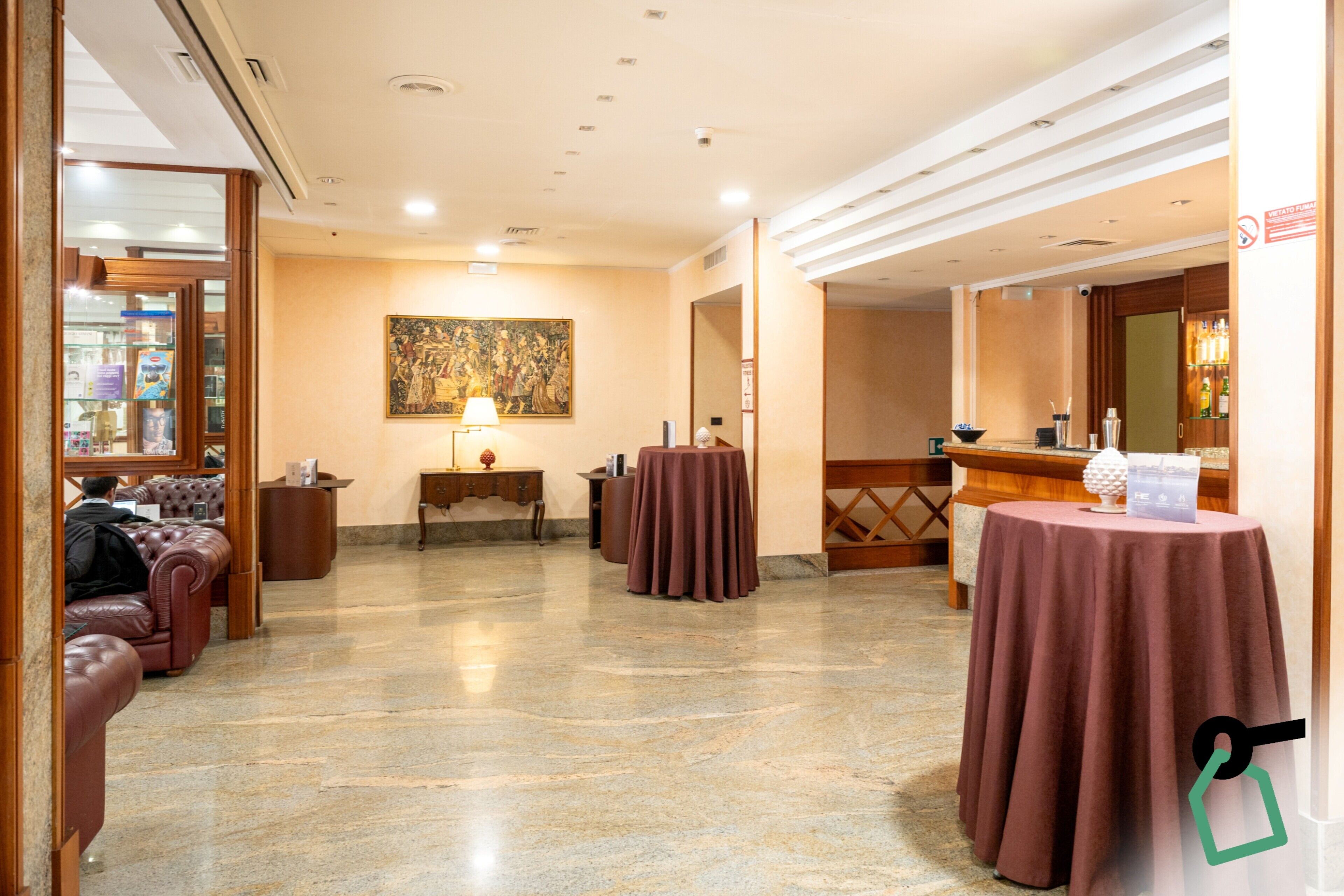 Um saguão de hotel com assentos, balcão de recepção, uma pintura e área de bar.