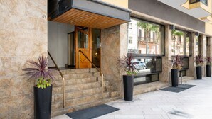L’entrée d’un hôtel, avec un escalier en bois, une porte en verre et des plantes en pot.