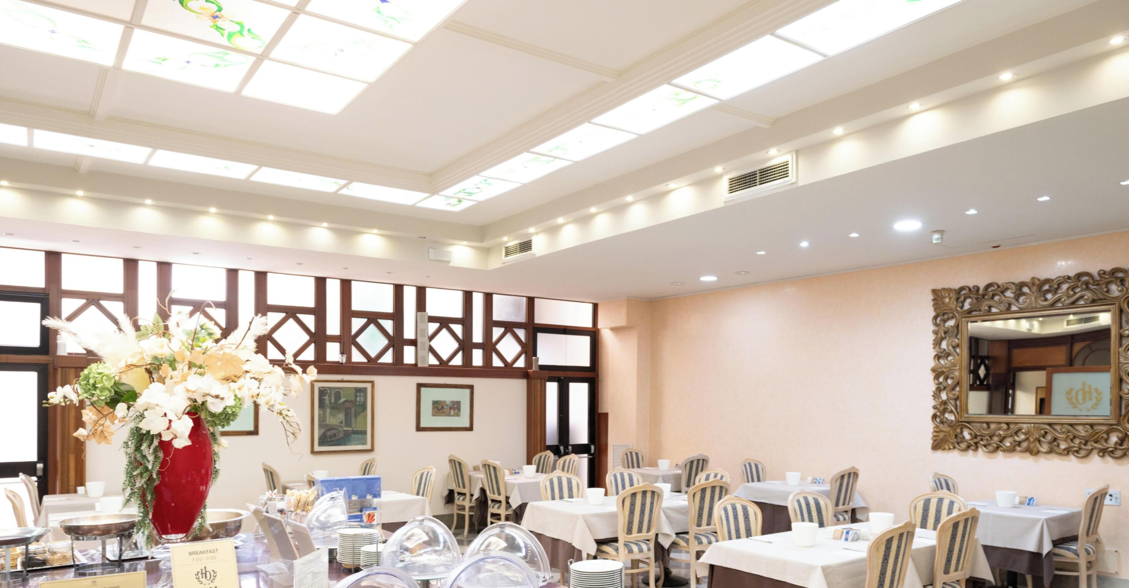 Un comedor con mesas, sillas y un jarrón decorativo.