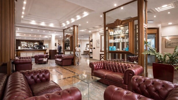 Un hall d’entrée spacieux, doté de canapés en cuir, d’un bar et d’un grand miroir qui reflète l’intérieur.
