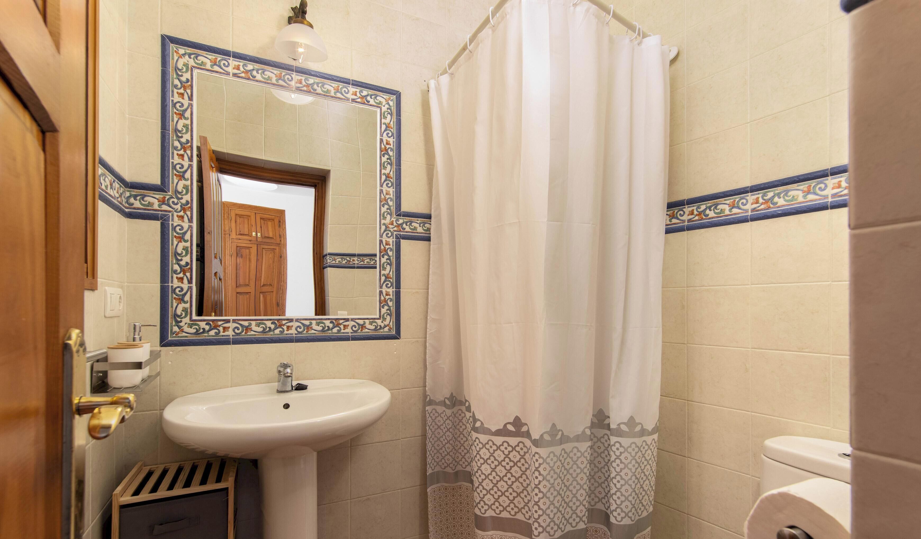 Une salle de bain équipée d’un lavabo, d’un miroir, de toilettes et d’un rideau de douche.