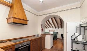 Eine Küche mit Holzarbeitsplatte, einem eingebauten Backofen, einer modernen Dunstabzugshaube und einer gefliesten Spritzschutzwand.