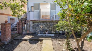 A residential building with a stone wall, a balcony with a metal railing, and a door leading to a room. - 'Fabian's House' with Sea View in Taormina (Taormina)