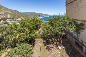 Un balcone con vista sul paesaggio costiero, che include una spiaggia e montagne.