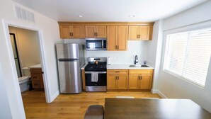 Una cocina compacta con armarios de madera, electrodomésticos de acero inoxidable y un ventanal que proporciona luz natural.