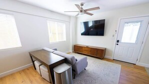 Una sala de estar con sofá, mesa de comedor, televisor y ventilador de techo.