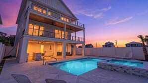 Un bâtiment à deux étages doté d’une piscine, d’un espace extérieur aménagé et offrant une vue sur le ciel au coucher du soleil.