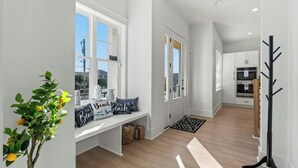Un couloir avec un banc, un porte-manteau et une vue sur la cuisine.