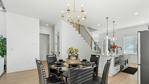 Une cuisine moderne dotée d’un îlot central, d’un lustre et d’un escalier menant à un autre niveau.