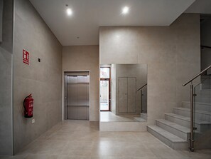 Ein modernes Interieur mit Feuerlöscher, Aufzug und Treppe.